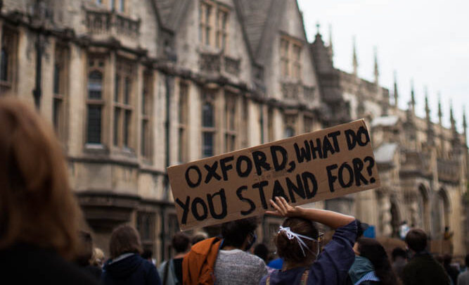 Oxford BLM Protest Image featuring a person holding a sign that reads 'Oxford, What do you stand for?' by Emily Jarrett Photography