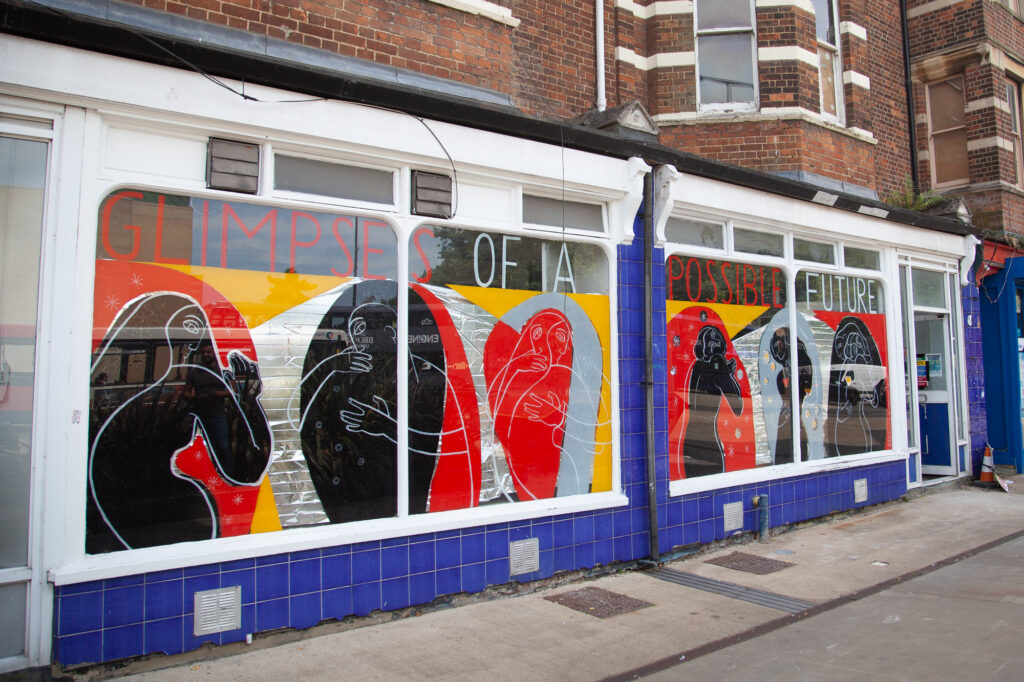 A red, black and grey mural of figures embracing on the front of a building
