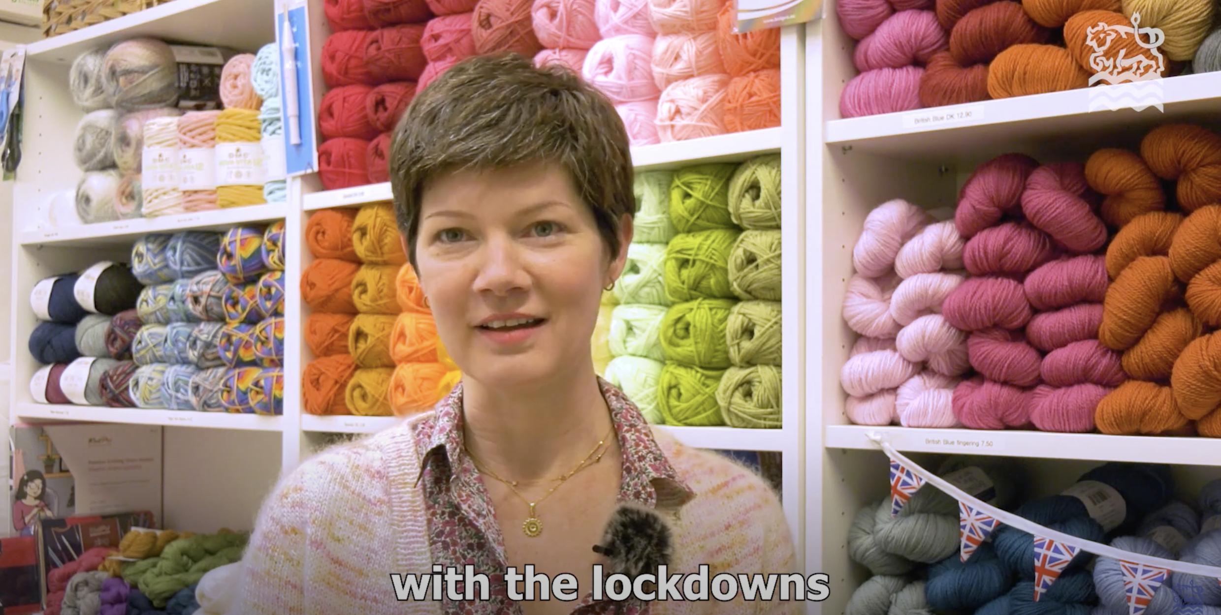 Screenshot of Jess from OCC MiO Video in front of shelves of brightly coloured wool