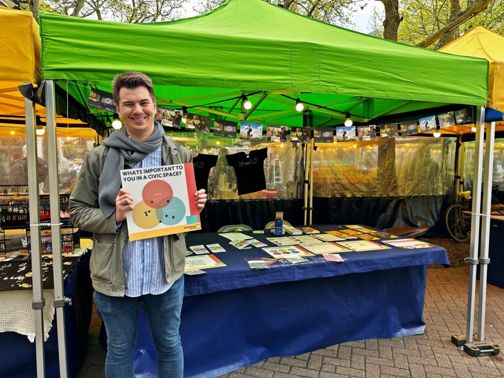 A man, Alex Lui, standing in front of a market stall