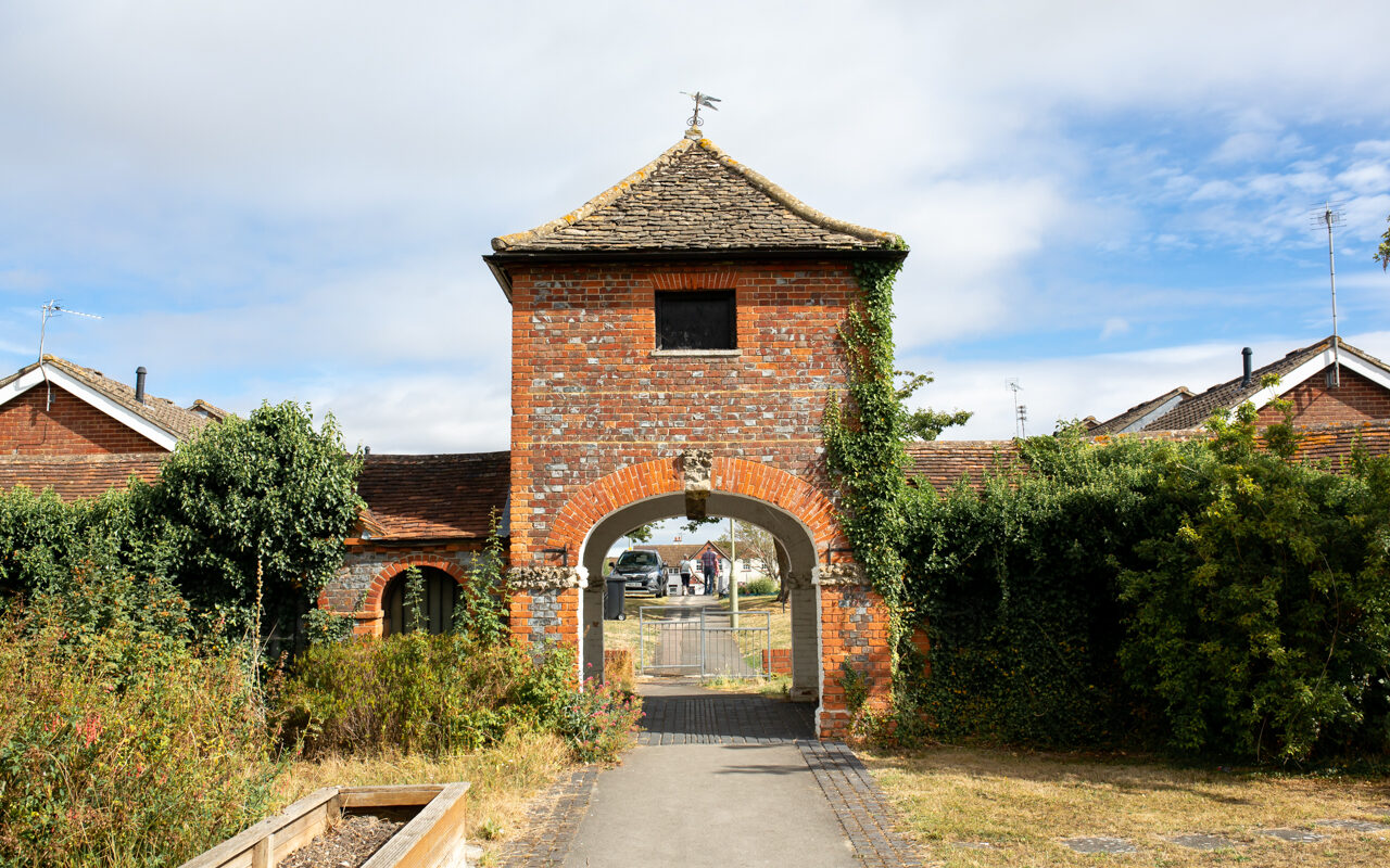 Entryway to The Old Stables, a red brick gatehouse style building with an archway