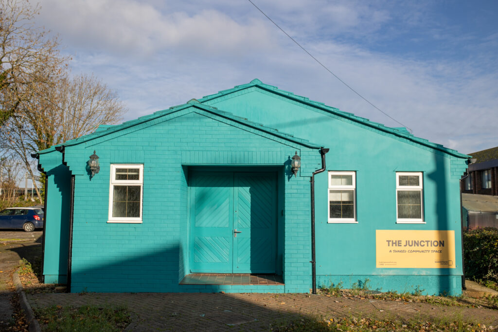 Nov7.22-4332 The exterior of The Junction, a bright blue building with three windows and a large double door