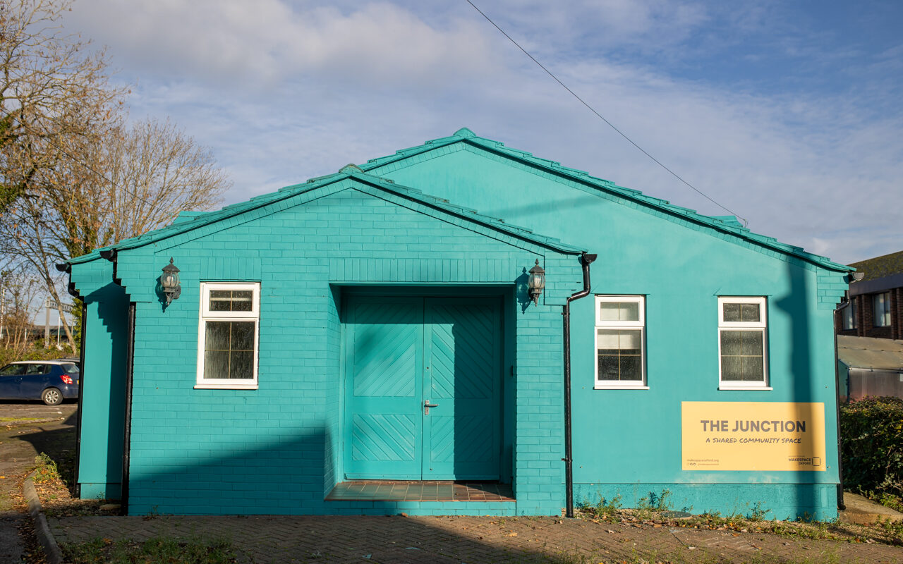 The exterior of The Junction, a bright blue building with three windows and a large double door