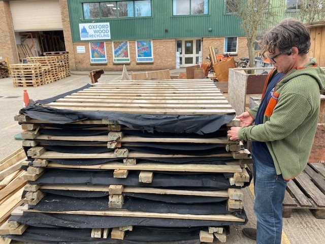 Adrian Sell looking at a stack of wooden pallets
