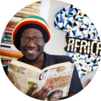 Picture of Natty Mark Samuels, smiling for the camera while holding an open book