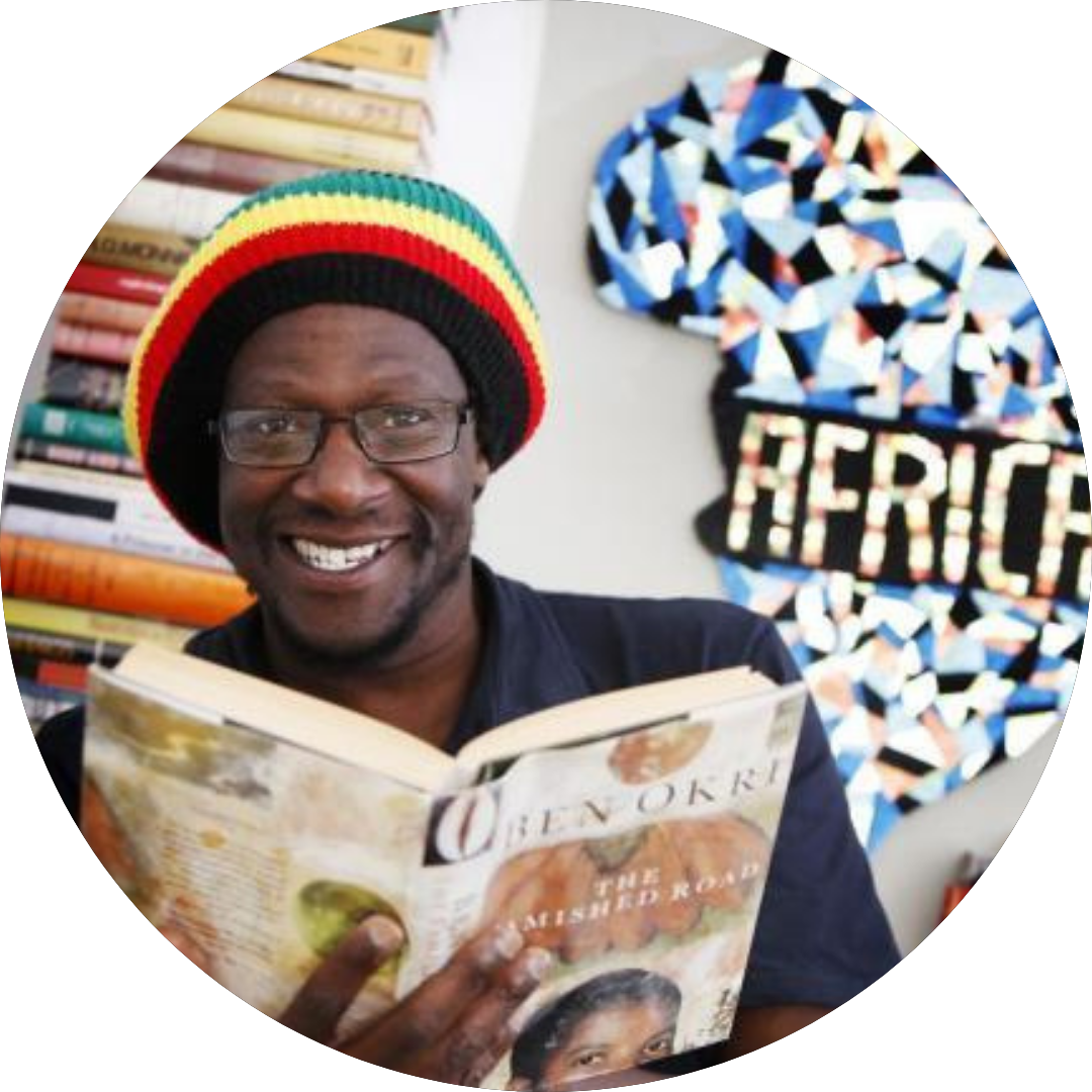 Picture of Natty Mark Samuels, smiling for the camera while holding an open book