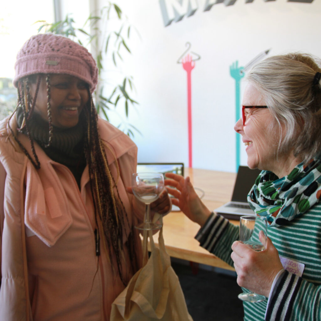 Two Makespace residents in conversation, holding glasses of wine